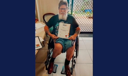 Man in wheelchair holding certificate