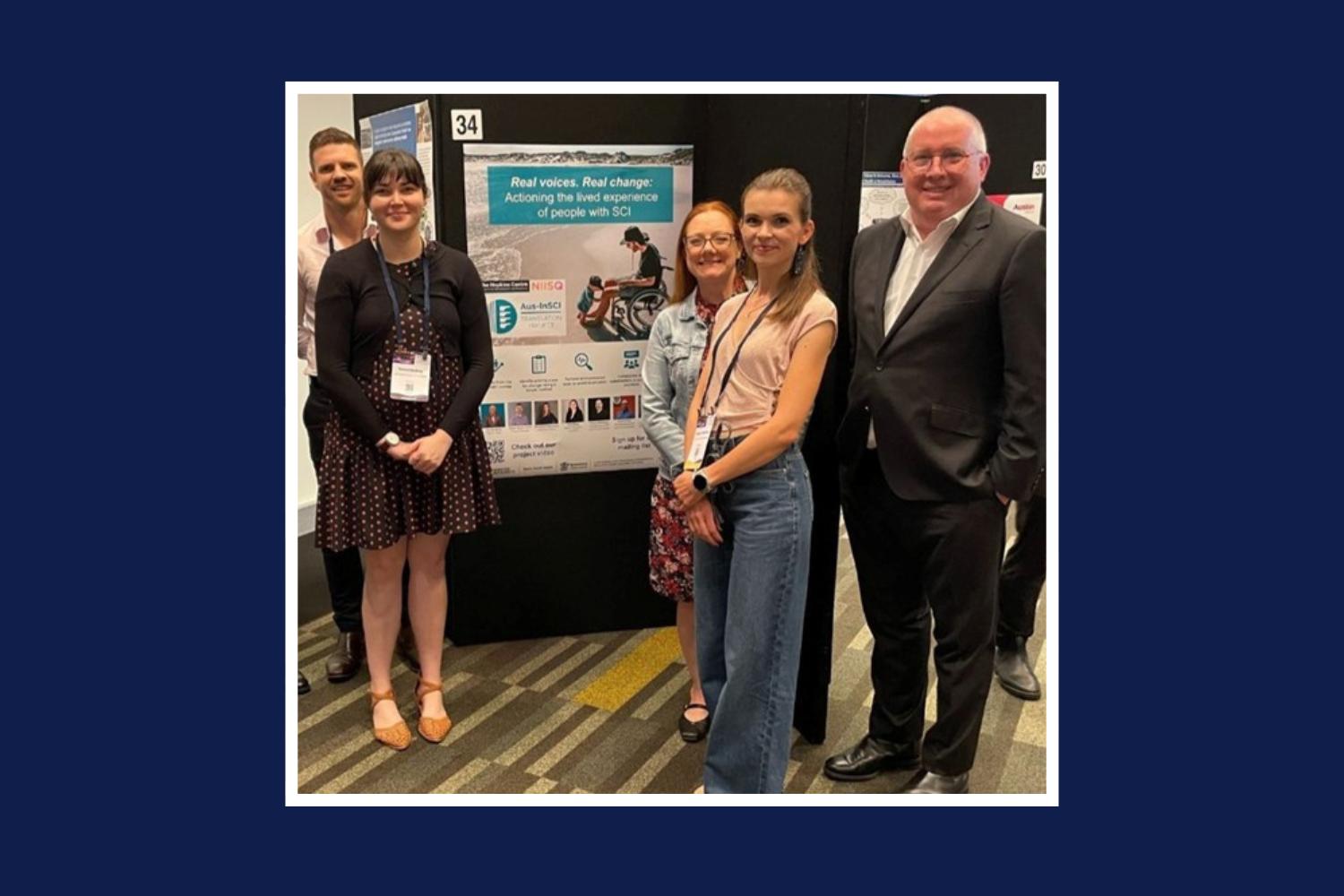 An image of five people standing in front of a research poster titled "Real voices. Real change: Activating lived experience of people with SCI." The image has a white boarder and is on a navy-blue background.